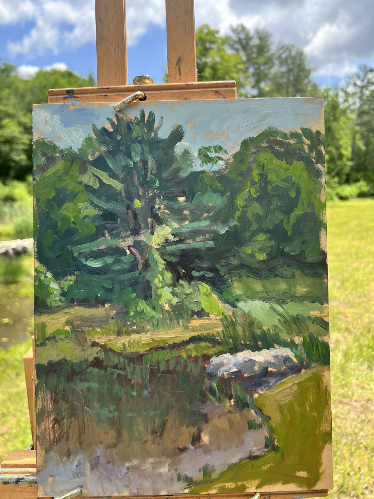 Plein-air oil painting of trees and the pond on an easel, by Elena Rykoff